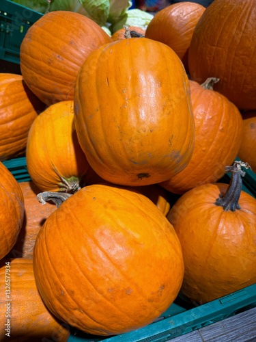 Several large, orange pumpkins displayed on a vegetable market stall, rustic market setting