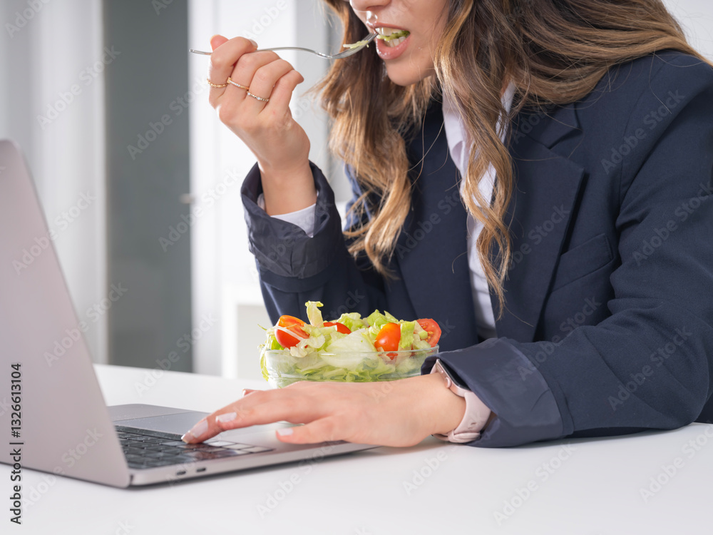 Businesswoman eating salad, close up image of young caucasian brunette businesswoman eating salad at desk in office while working no time for lunch break wear formal suit. Healthy lifestyle concept. Businesswoman eating salad, close up image of young caucasian brunette businesswoman eating salad at desk in office while working no time for lunch break wear formal suit. Healthy lifestyle concept.