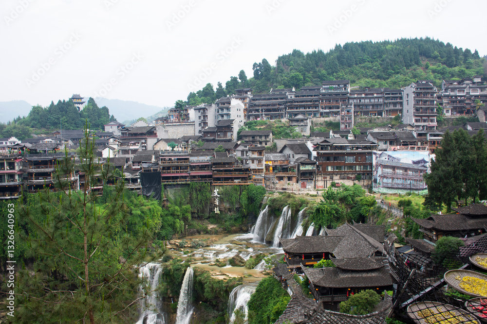 Obraz premium Cityscape historic building antique architecture of Furong Zhen Tujia ancient town with landscape mountain waterfall and youshui river for chinese travelers travel visit on May 9, 2024 in Hunan, China