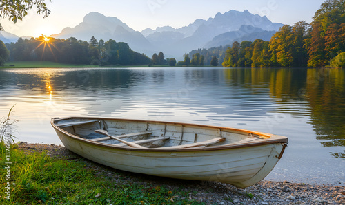 A serene morning scene featuring a boat by a tranquil lake surrounded by mountains and lush trees, illuminated by soft sunlight.