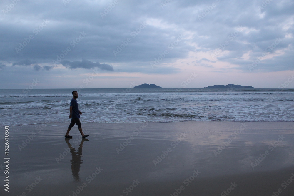 Naklejka premium homem caminhando em praia no nascer do sol em florianópolis, santa catarina