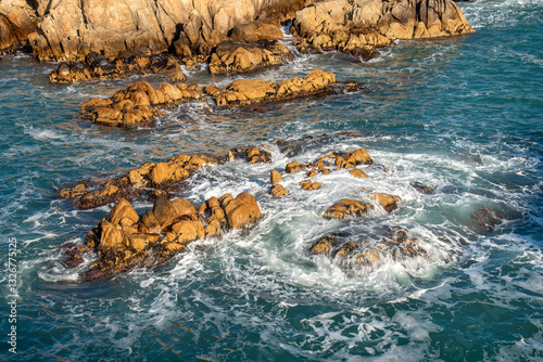Coastline rock formations at sunrise with a swirling waves braking against the rocks