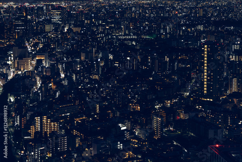 Dense urban landscape of Tokyo at night with illuminated buildings creating a geometric pattern of lights and shadows captured in a cinematic film-like color grading