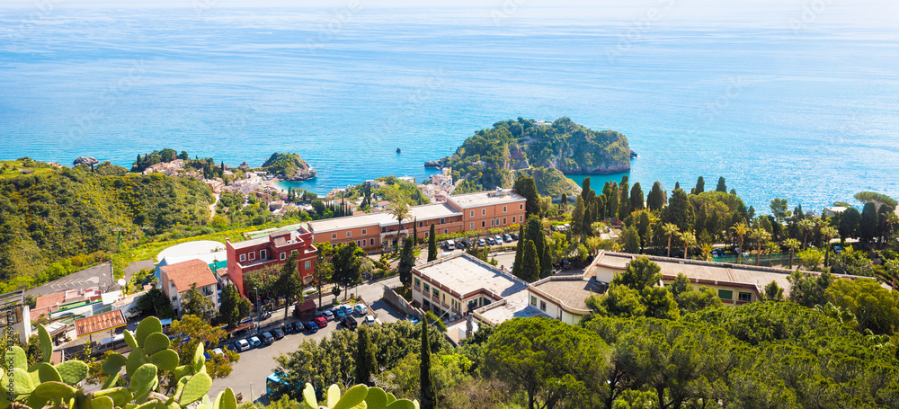 Fototapeta premium Panoramic aerial view of picturesque coastline of Taormina in Sicily, Italy with vibrant blue waters of Mediterranean sea, lush greenery and luxury hotels. Welcome to Taormina concept image