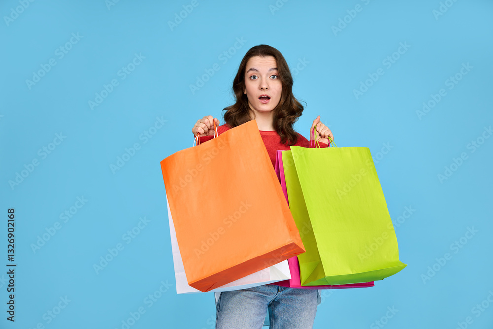Cute surprised girl with shopping bags isolated on blue background. Cute surprised girl with shopping bags isolated on blue background.