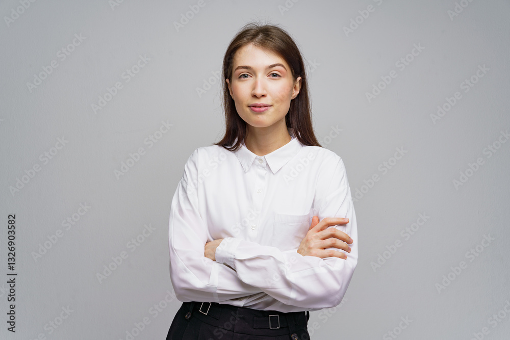 Confident young woman poses with folded arms in a neutral background, exuding professionalism and poise Confident young woman poses with folded arms in a neutral background, exuding professionalism and poise