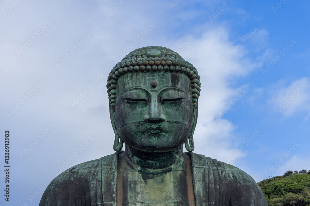 The iconic Great Buddha statue at Kotoku-in temple in Kamakura Japan captured from the front emphasizing the aged bronze surface intricate details and serene expression against the sky The iconic Great Buddha statue at Kotoku-in temple in Kamakura Japan captured from the front emphasizing the aged bronze surface intricate details and serene expression against the sky