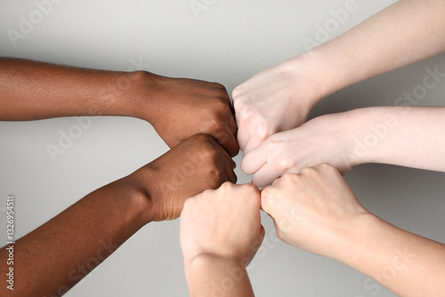 Stop racism. People of different skin colors bumping fists on light grey background, closeup