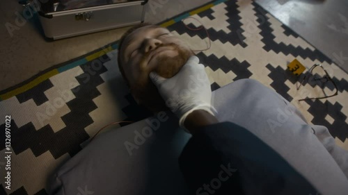 POV shot of unrecognizable detective agent in sterile gloves examining corpse of young Caucasian man lying on floor with signs of suffocation