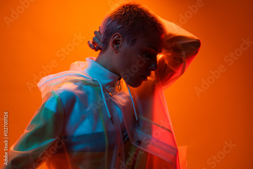Portrait of a person standing against an orange backdrop, illuminated by dynamic colorful lighting, evoking creativity and modern art aesthetics with contemporary fashion style.