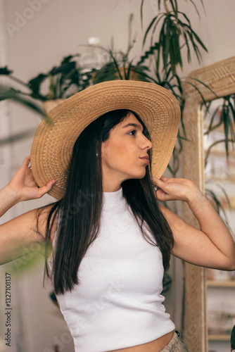 Obraz na płótnie Portrait of a happy young dark-haired woman in a straw hat in a room with indoor plants.Summer concept. w salonie