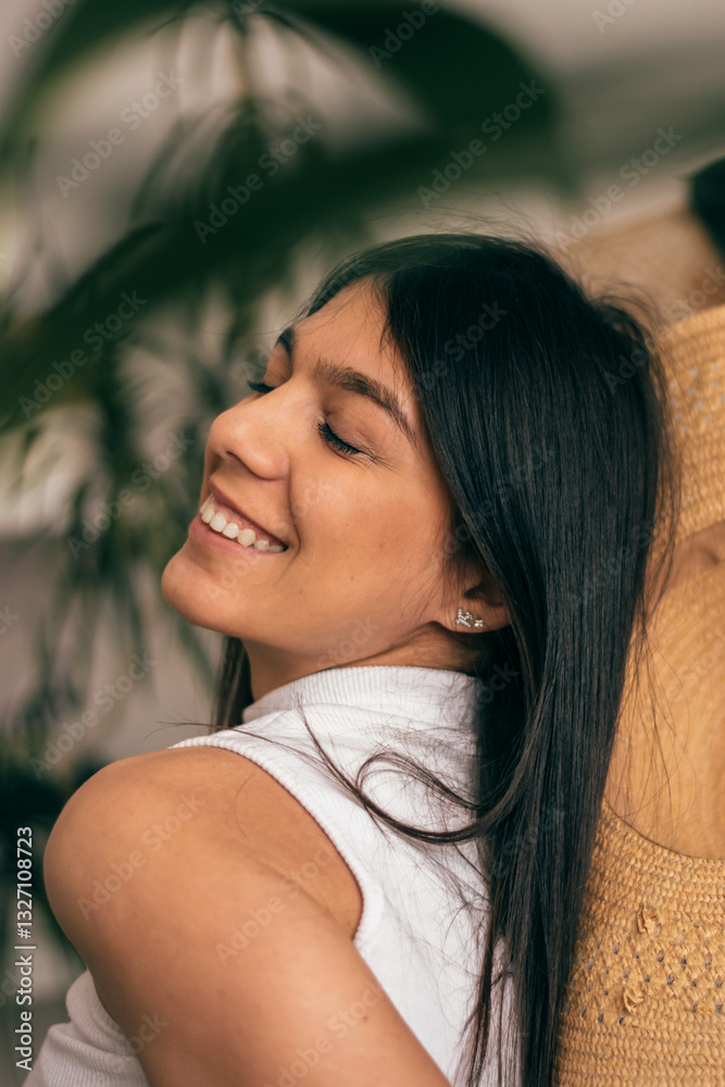 Portrait of a happy young dark-haired woman in a straw hat in a room with indoor plants.Summer concept.