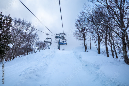 Chairlift cableway in Gala Yuzawa ski resort to famous point top of the snow mountain, Bell of Love, under snow falling in winter season, Yuzawa, Japan photo