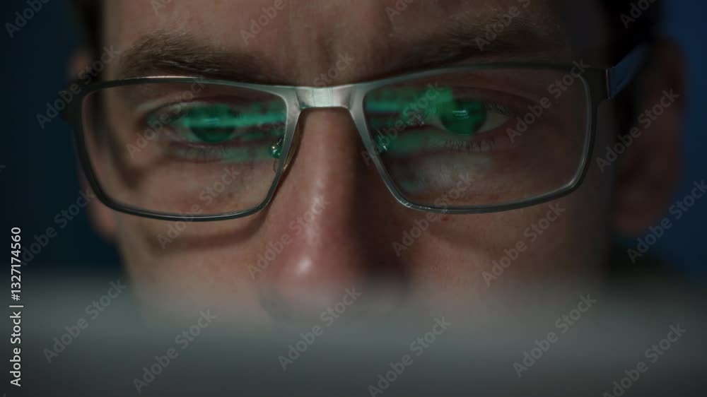 Close-up of a focused coder with glasses, writing a script. Programming code reflecting on developers eyeglasses 