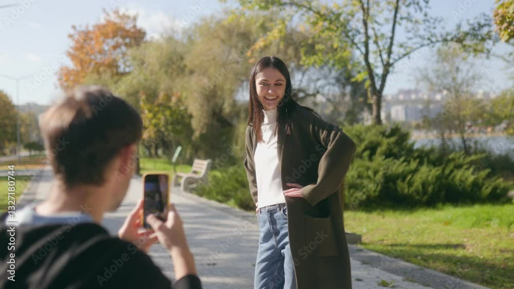 Loving Couple Enjoys Fall Day, Husband Taking Photos of His Wife in Park Loving Couple Enjoys Fall Day, Husband Taking Photos of His Wife in Park