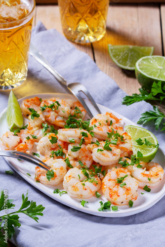 Obraz na płótnie Shrimp cooked with garlic and herbs, served with beer and lime on a wooden table. w salonie