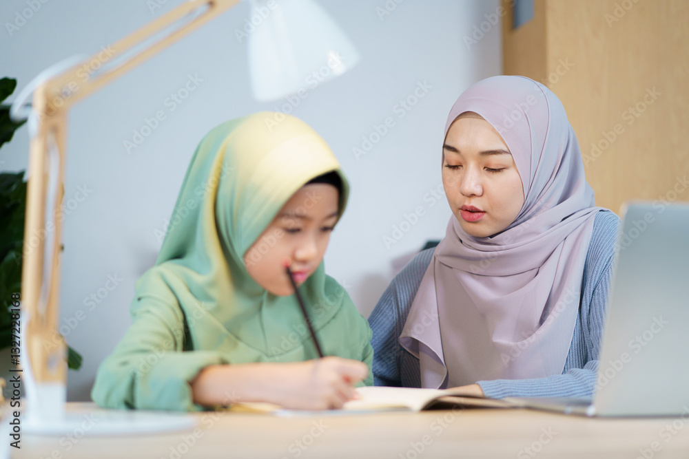 Asian muslim woman is teaching and reviewing homework with her daughter. Asian muslim woman is teaching and reviewing homework with her daughter.