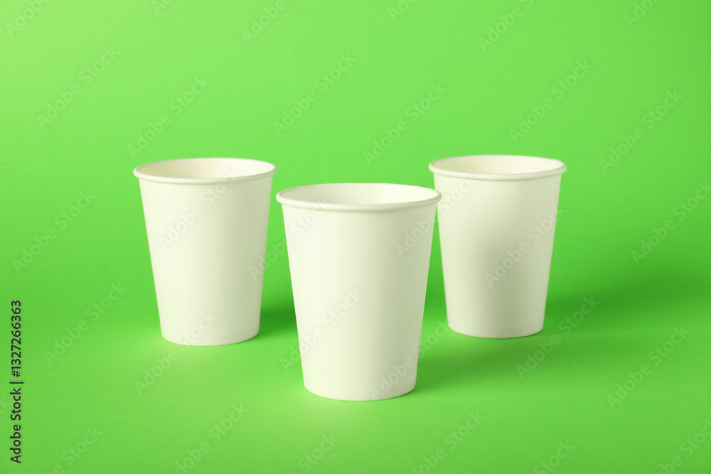 Paper cups on green background. Mockup for design Paper cups on green background. Mockup for design