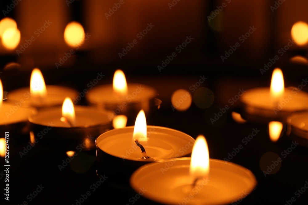 Many burning candles on dark surface, closeup