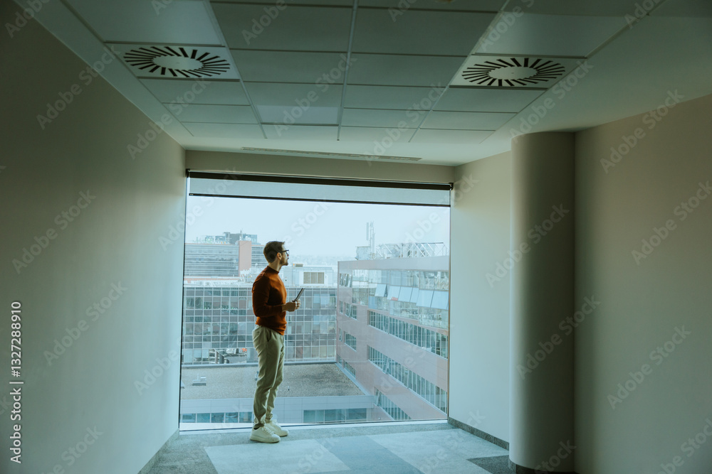 Man enjoying a quiet moment while gazing out of a large window in a modern building Man enjoying a quiet moment while gazing out of a large window in a modern building