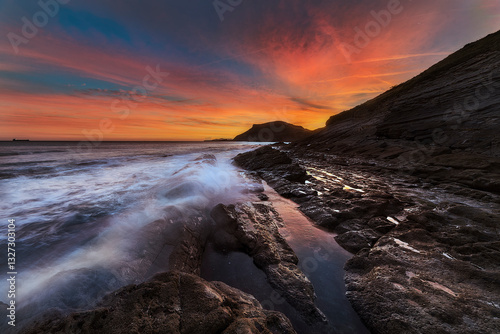 Warm sunrise over the Cantabrian Sea in Kobaron, Bizkaia, with the beach between the rocks of the coast.
