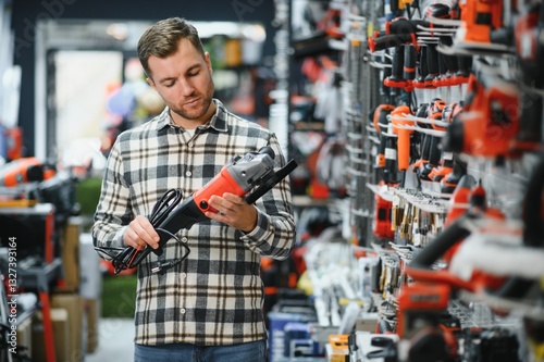 A male buyer chooses power tools in a hardware store. A large selection of tools