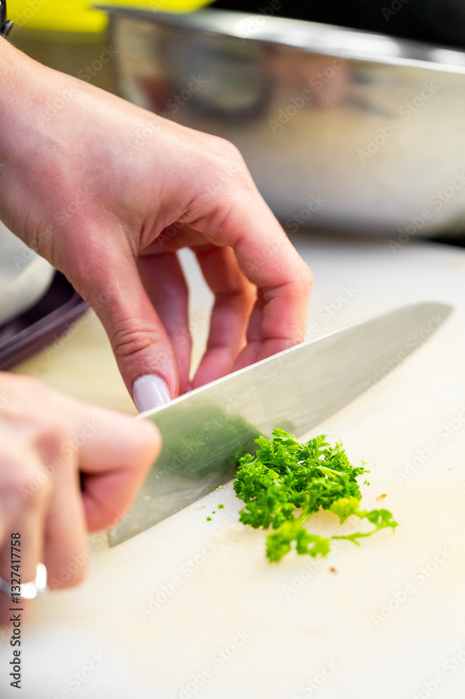 A close-up of a hand skillfully chopping fresh green herbs on a wooden cutting board, with a stainless-steel knife. The culinary scene captures the essence of cooking. A close-up of a hand skillfully chopping fresh green herbs on a wooden cutting board, with a stainless-steel knife. The culinary scene captures the essence of cooking.