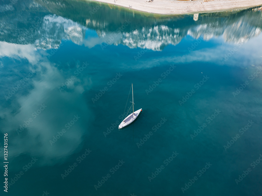 Fototapeta premium Aerial drone view of Lake Molveno, beautiful lake in Italy. Lake in dolomites from drone in winter. Lake Molveno in Italy. Sailboat, yacht on crystal clear lake in the Brenta Dolomites