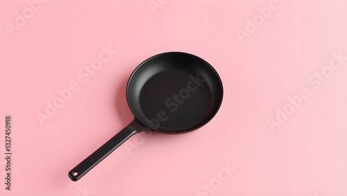 A minimalist photograph of a black cast iron skillet lying on a soft pink surface. The skillet has a smooth, matte finish and a long, straight handle