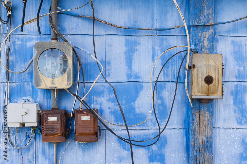 Old electrical meters and equipment on a blue wall.