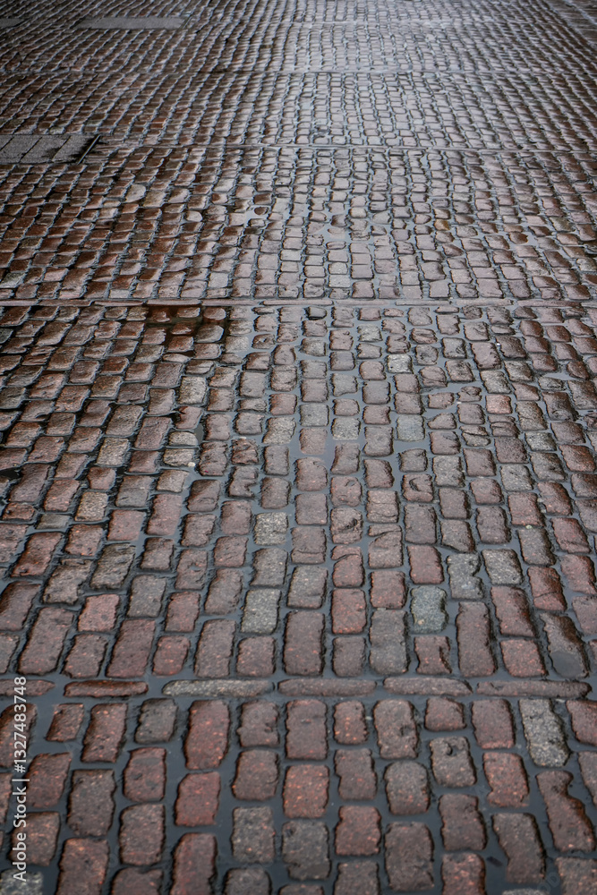 Wet cobblestone road or pavement, water between stone tiles