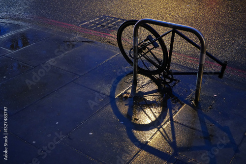 Obraz na płótnie Rear wheel of a bike chained to metal pipe at night street, other parts already stolen w salonie
