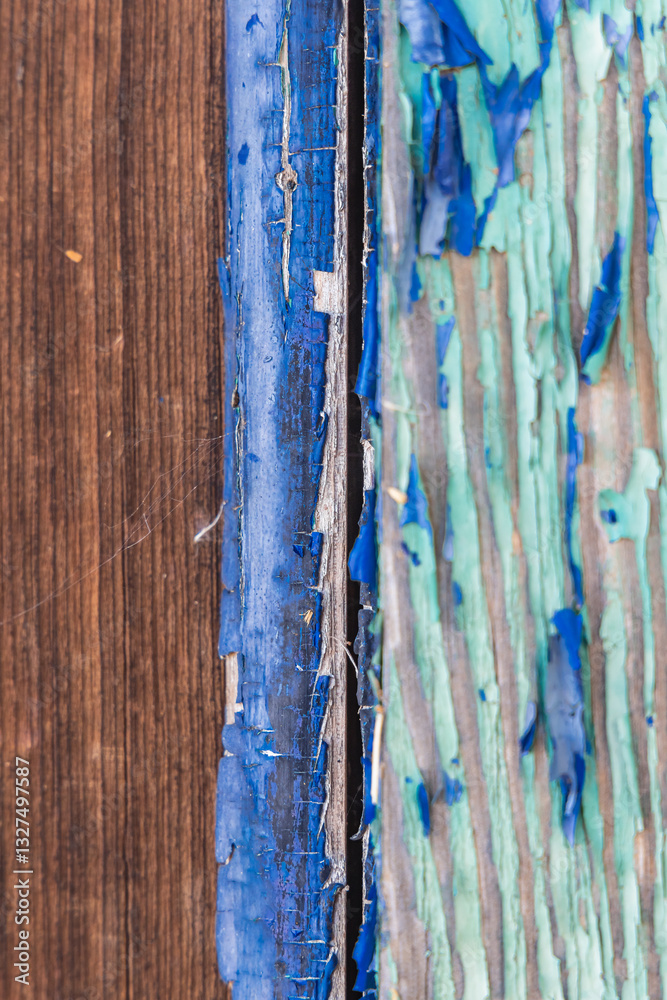 Blue and green peeling paint on an old wooden building.
