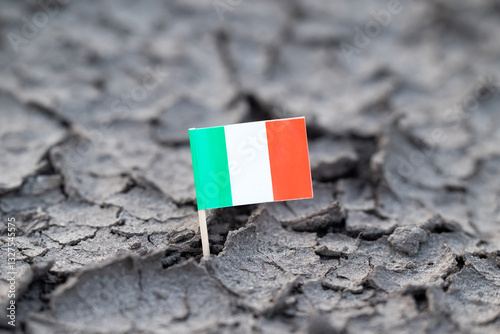 Flag of Italy on dry cracked soil. Concept of drought in Italy, hot rainless season, lack of water