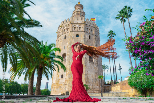 Mujer típica española bailando flamenco con una torre medieval y el cielo a su espalda. Desde la ciudad de Sevilla, Andalucía, España, Europa.	