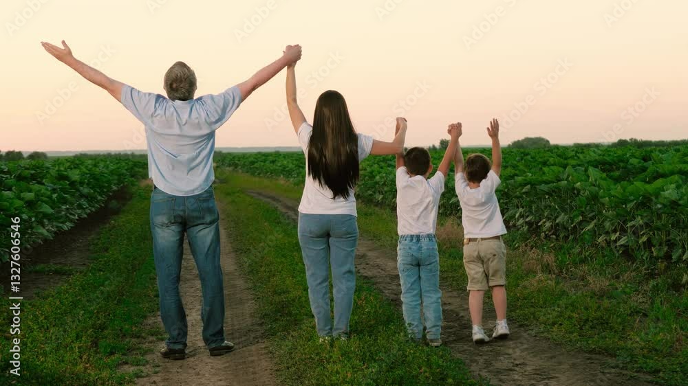 Cheerful family with children raises up hands standing in field on summer vocation. Happy parents and children enjoy being together in nature park at twilight. Children with parents raise hands Cheerful family with children raises up hands standing in field on summer vocation. Happy parents and children enjoy being together in nature park at twilight. Children with parents raise hands