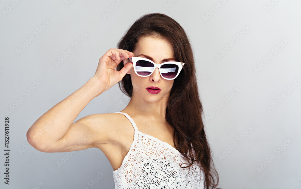 Studio closeup portrait of elegant woman posing in retro white sunglasses and fashion white top and holding hand glasses on wall background with empty copy space. Emotion sexy Studio closeup portrait of elegant woman posing in retro white sunglasses and fashion white top and holding hand glasses on wall background with empty copy space. Emotion sexy
