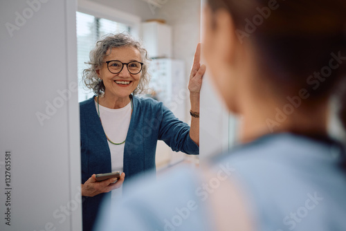 Happy senior woman greeting visiting nurse at home.