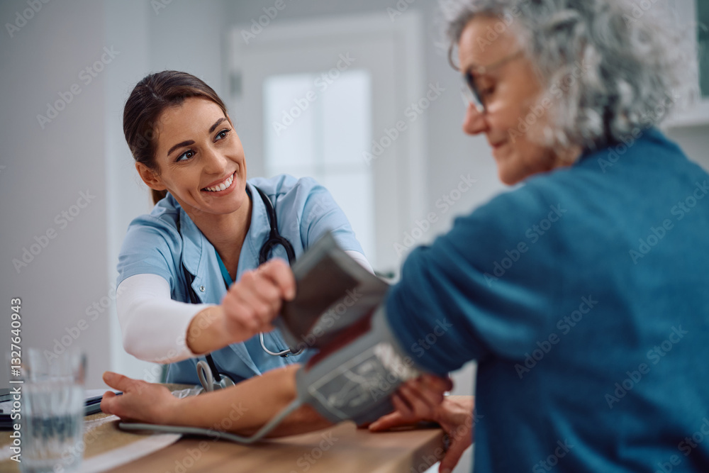 Fototapeta premium Smiling nurse measuring blood pressure of mature mature woman during home visit.