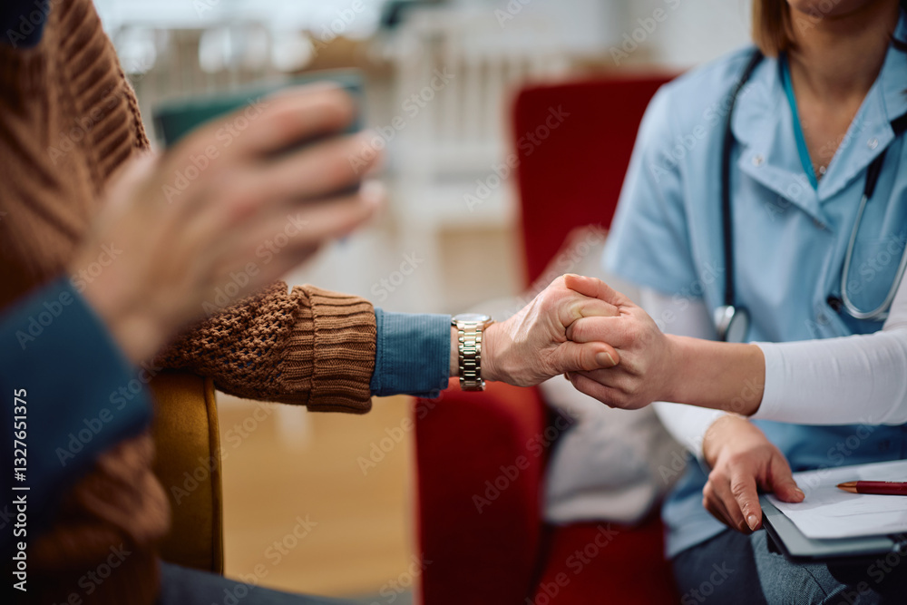 Obraz premium Close up of elderly woman holding hands with nurse during home visit.