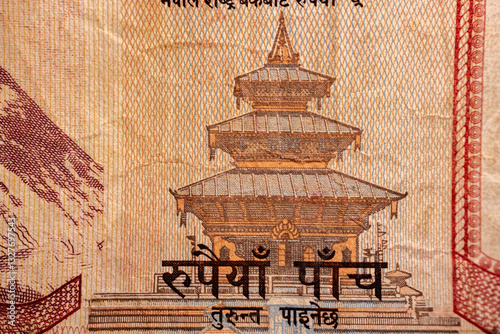 A macro shot of a Nepalese Rupee 5 banknote displaying an intricate engraving of two yaks in a mountainous landscape. The note's texture, design, and details are visible.