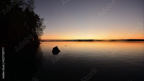 Time-lapse of a summer morning with the sky coloured by the rising sun by a lake in the forests of Finland