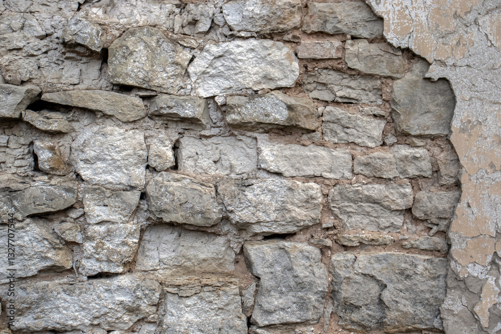 A wall made of limestone stones. The stones have crumbled in the wall of the building due to time and weather. The wall was built from the stones in ancient times. A wall made of limestone stones. The stones have crumbled in the wall of the building due to time and weather. The wall was built from the stones in ancient times.