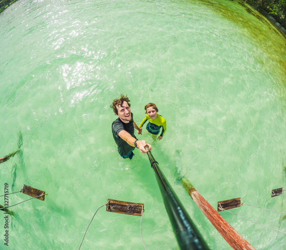 Father and son enjoying the serene beauty of Lake Bacalar, Mexico. Together, they connect with nature, having a memorable outdoor experience in this peaceful tropical destination
