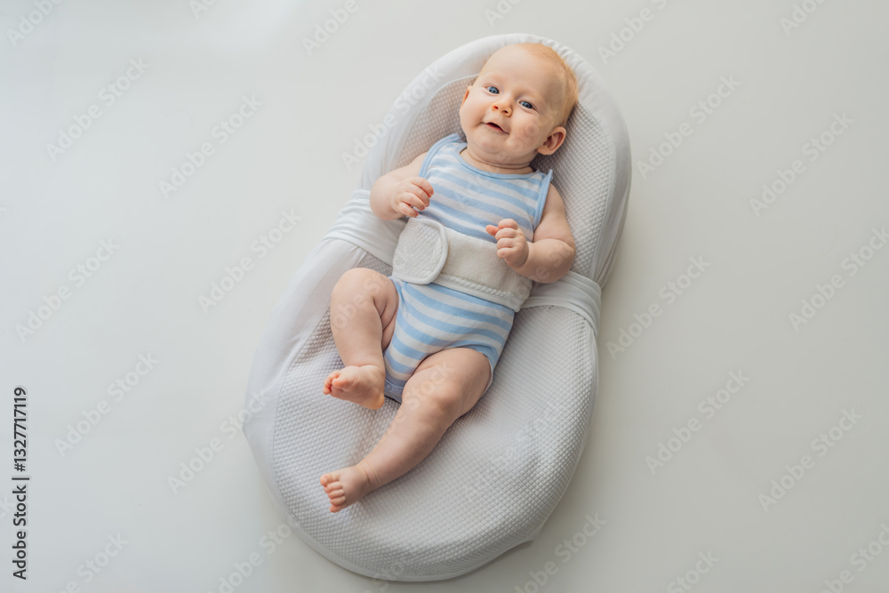 Adorable 3-month-old baby lying safely in a cozy infant cocoon secured with a special safety belt. Comfortable and protective design for newborn care. Parenting, safety, and baby comfort concept
