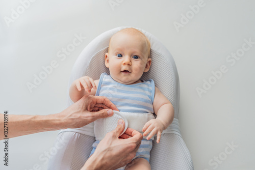 Obraz na płótnie Adorable 3-month-old baby lying safely in a cozy infant cocoon secured with a special safety belt. Comfortable and protective design for newborn care. Parenting, safety, and baby comfort concept w salonie