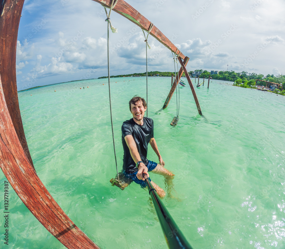 Male tourist enjoying a swing over the turquoise waters of Lake Bacalar, Mexico. A fun and adventurous experience in nature, capturing the essence of outdoor leisure and water exploration