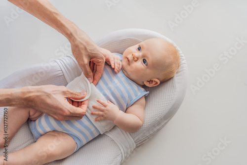 Obraz na płótnie Adorable 3-month-old baby lying safely in a cozy infant cocoon secured with a special safety belt. Comfortable and protective design for newborn care. Parenting, safety, and baby comfort concept w salonie