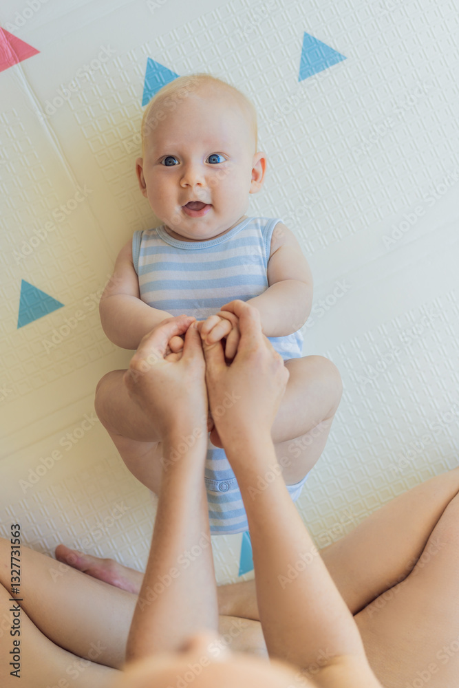 A mother practices baby gymnastics with her 3-month-old on a soft children's play mat. A joyful and nurturing moment focused on bonding, development, and care. Early childhood, fitness, and parenting