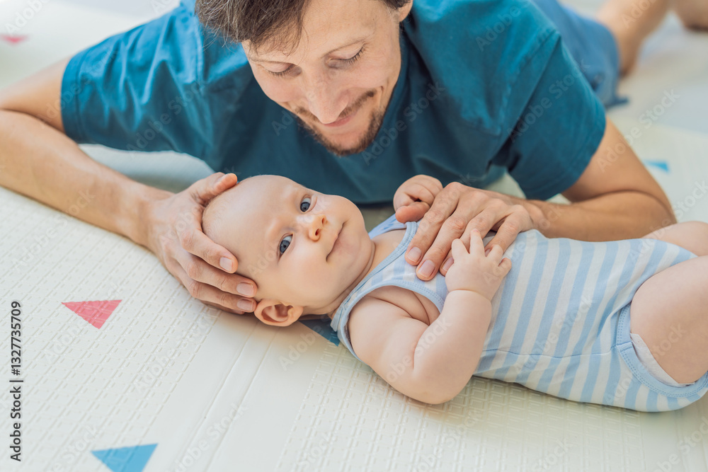 A baby lies on a soft children play mat while their father hands gently support and protect them. Heartwarming moment of care and connection. Parenthood, safety, and love concept